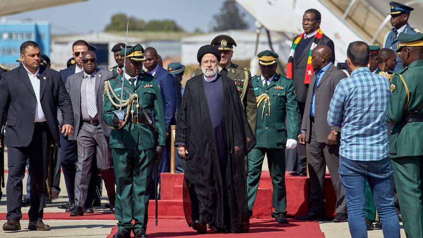 Iranian President Ebrahim Raisi (C) inspects the guard of honor upon his arrival for a state visit at the Robert Gabriel Mugabe International Airport in Harare on July 13, 2023. 